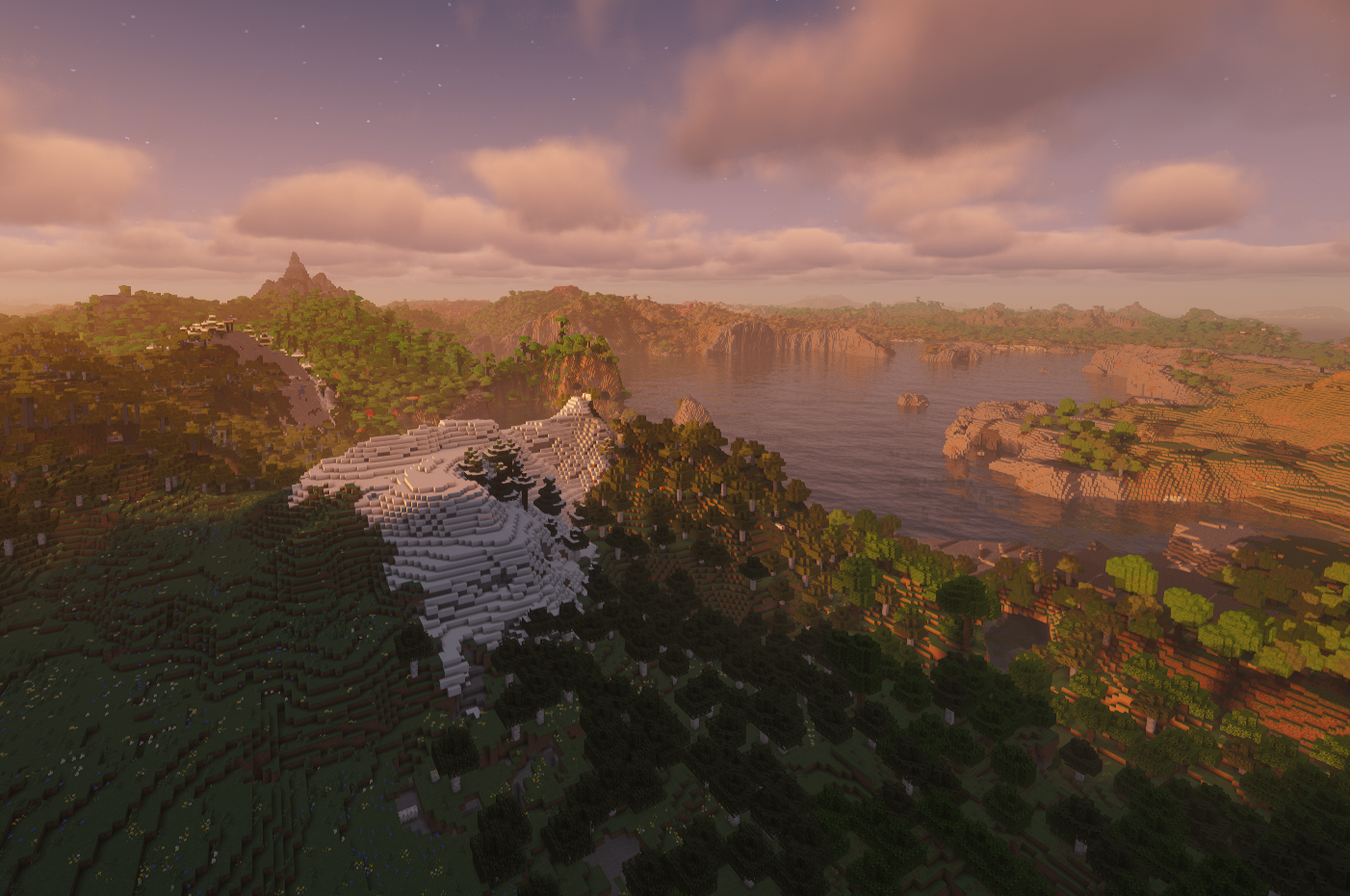 Sunset view across forests, snowy mountains, and a lake in the UMBC Minecraft server world